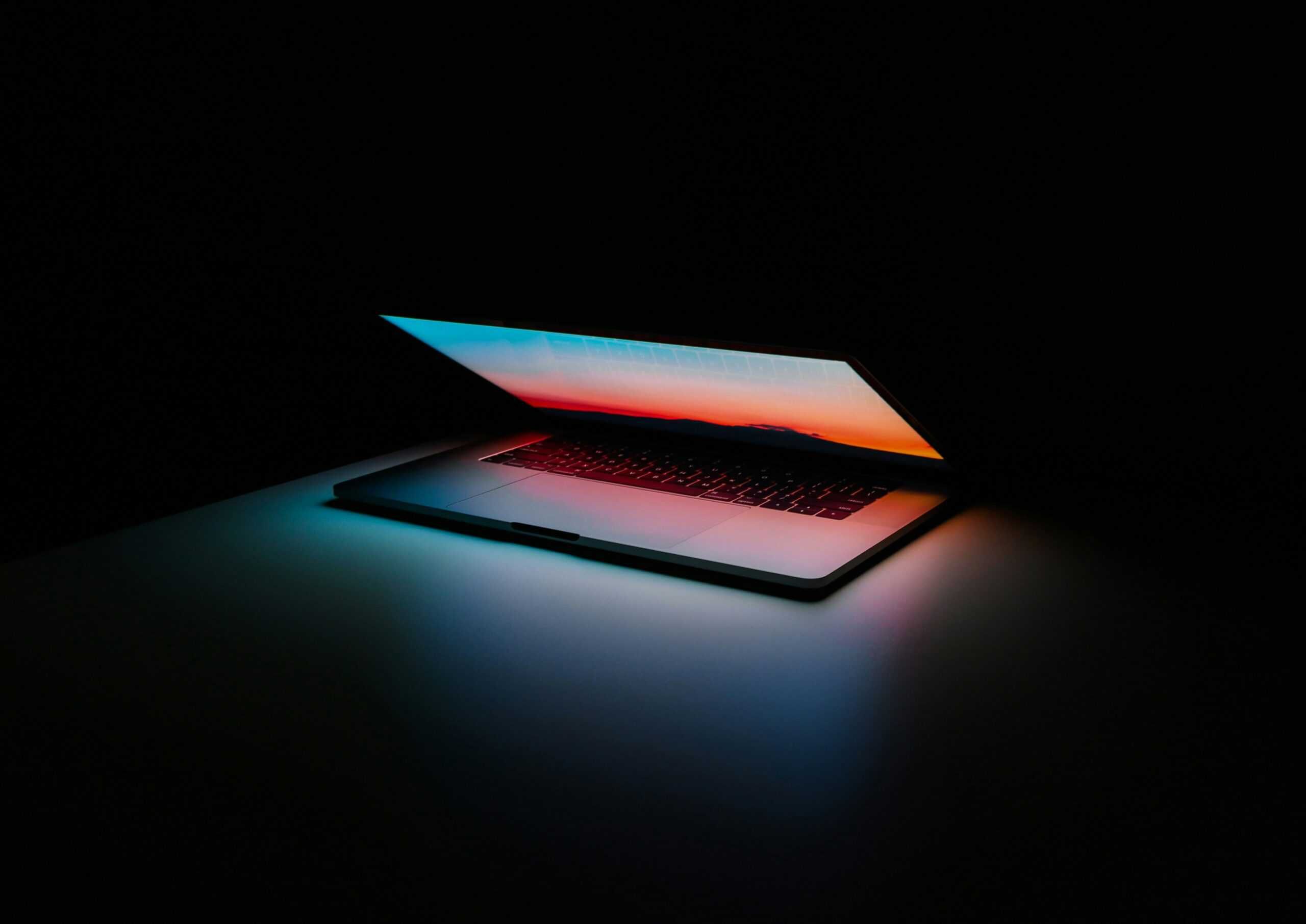 A dark room with a half-open mac laptop screen.