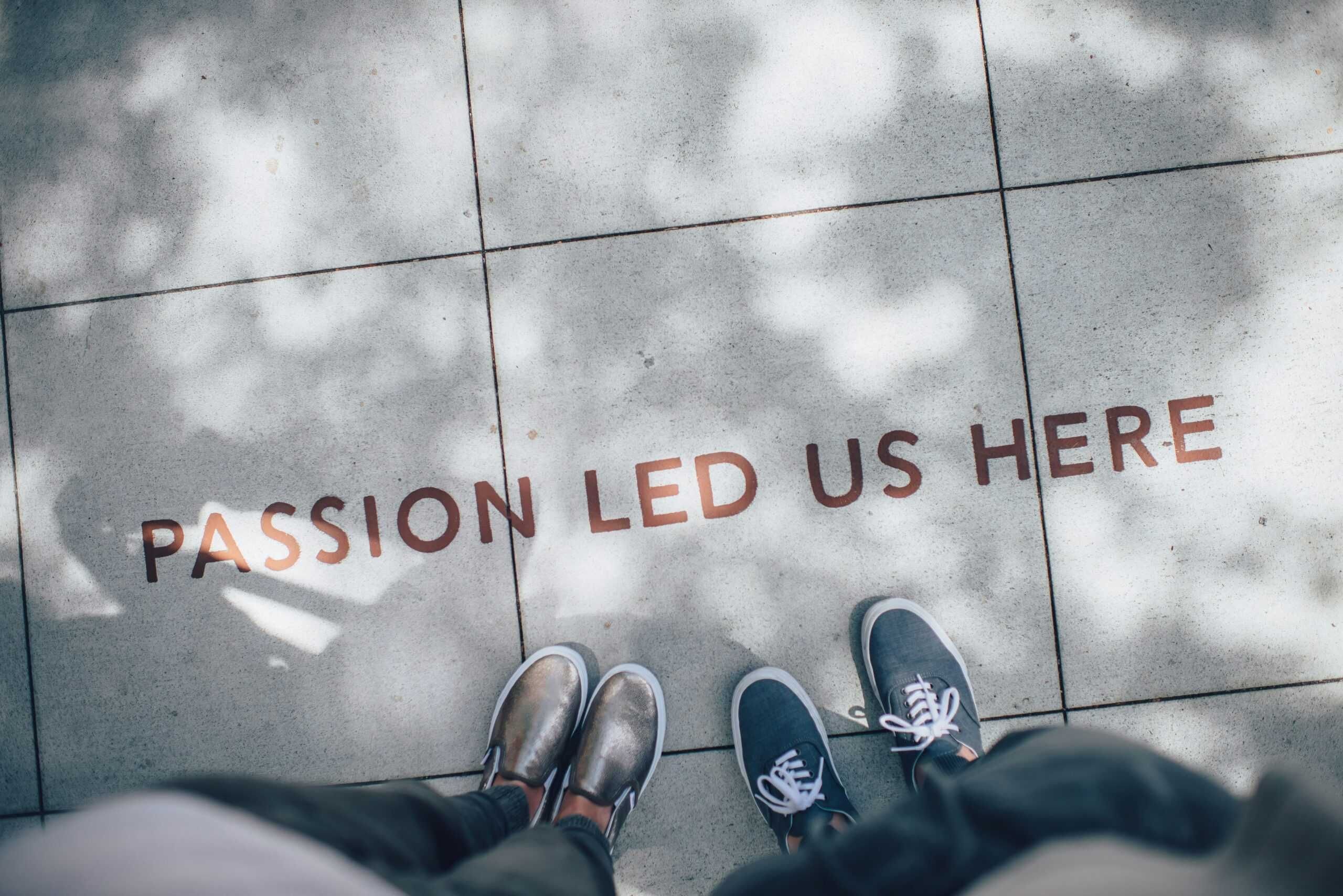 A sidewalk with the sign "PASSION LED US HERE" written in red letters.