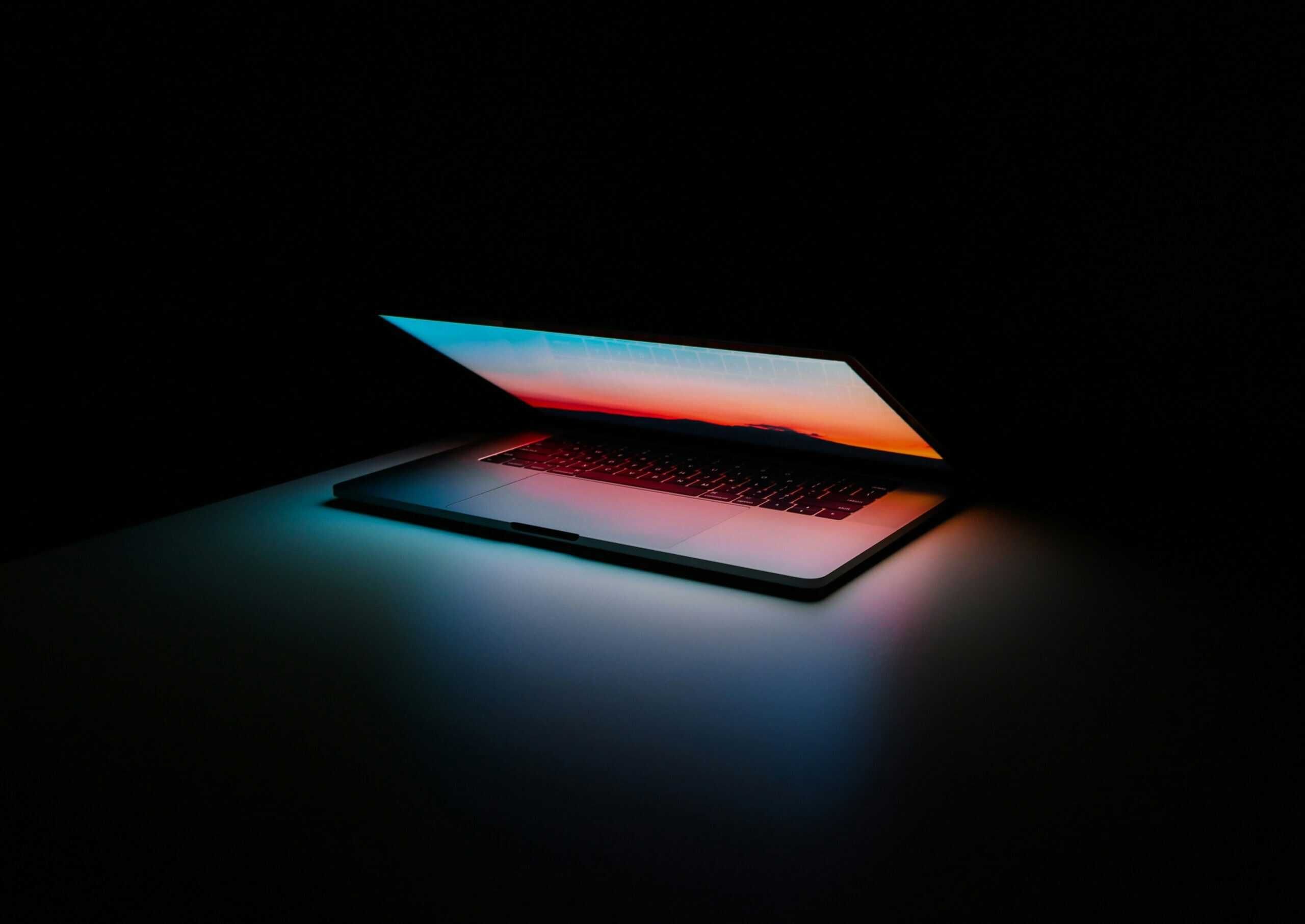 A dark room with a half-open laptop.