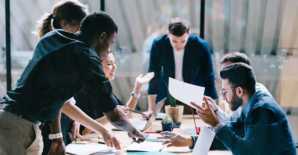 Several people are working together around the table at an office.