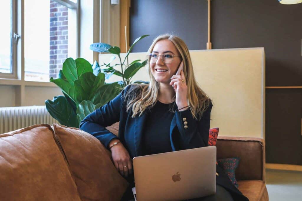 A woman on her phone is sitting on a brown sofa.